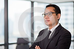 Portrait of confident asian business man in eyeglasses standing in offiec