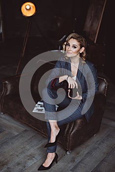 Portrait of a confident beautiful business woman in a suit on a dark background holds a camera in her hands. The concept of gender