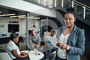 Portrait of a confident black African businesswoman using her tablet looking into the camera