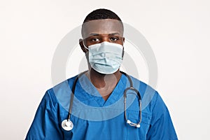 Portrait of confident black doctor in face mask over white photo