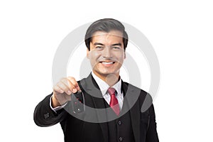 Portrait of a confident business man in black suit feeling happy and smile holding the keys of the car isolated on white