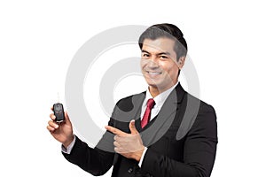 Portrait of a confident business man in black suit feeling happy and smile holding the keys of the car isolated on white