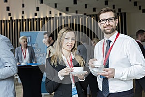 Portrait of confident business people holding coffee cups at lobby in convention center