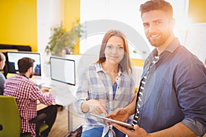 Portrait of confident business people using tablet computer at creative office