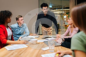 Portrait of confident business team leader standing surrounded by multiracial colleagues, confidently looking to staff