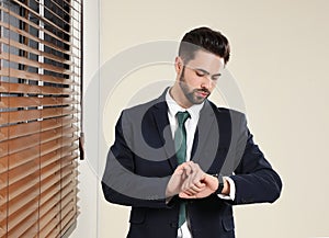 Portrait of confident businessman checking time at window