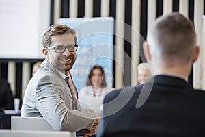 Portrait of confident businessman sitting in seminar hall