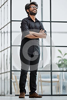 Portrait of a confident businessman standing with crossed arms in a conference room