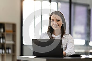 Portrait confident businesswoman working on laptop at her workplace at modern office.
