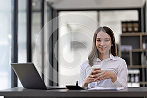 Portrait confident businesswoman working on laptop at her workplace at modern office.