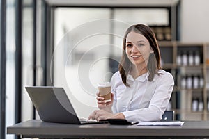 Portrait confident businesswoman working on laptop at her workplace at modern office.