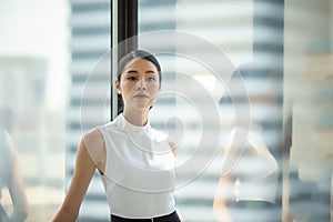 Portrait of confident businesswomen in office looking away by window