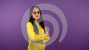 Portrait of confident calm asian woman in yellow sweater. woman on purple isolated background. the woman folded her arms