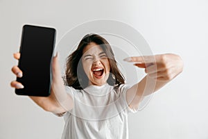 Portrait of a confident casual asian girl showing blank screen of mobile phone