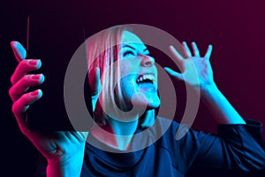 Portrait of a confident casual girl showing blank screen mobile phone isolated over blue background