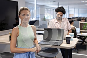 Portrait of confident cauasian businesswoman standing by laptop against biracial businesswoman photo