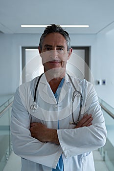 Male surgeon standing with arms crossed in the corridor in hospital