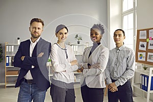 Group of happy diverse company employees standing in modern office and smiling at camera