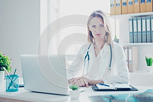 Portrait of confident concentrated medico wearing white coat, sh