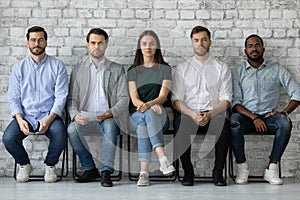 Portrait confident diverse candidates sitting in row, waiting for interview photo