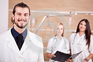 Portrait of confident doctor in front and nurses in blurred back