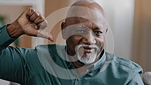Portrait of confident elderly african american man indoors looking at camera show thumb down negative emotion mature old