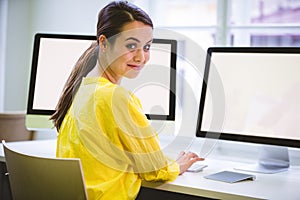 Portrait of confident executive with computer monitors at office