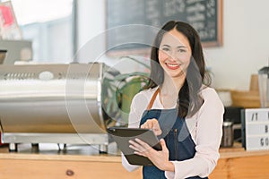 Portrait of confident female barista standing at counter. Woman cafe owner in apron looking at camera and smiling while