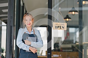 Portrait of confident female barista standing at counter. Woman cafe owner in apron looking at camera and smiling while