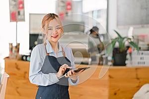 Portrait of confident female barista standing at counter. Woman cafe owner in apron looking at camera and smiling while