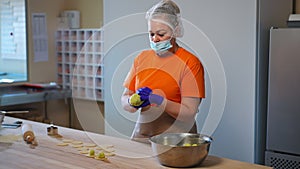 Portrait of confident female cook making potato balls placing ingredient in round dough pieces on wooden table in