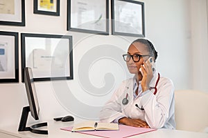 Portrait of confident female doctor answering call in office