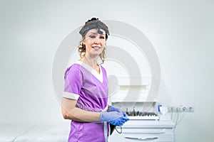 Portrait of confident female doctor. Female ENT doctor in purple medical clothes posing in office of the clinic on her