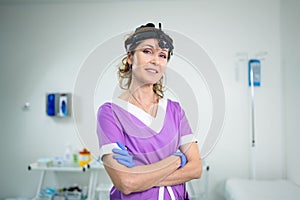 Portrait of confident female doctor. Female ENT doctor in purple medical clothes posing in office of the clinic on her