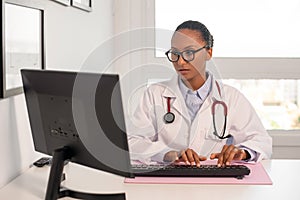 Portrait of confident female doctor working at computer