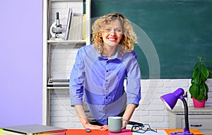 Portrait of confident female teacher in classroom. Smiling teacher in class at elementary school. Pretty teacher giving