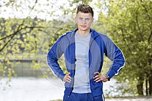 Portrait of confident fit man standing with hands on hips in park