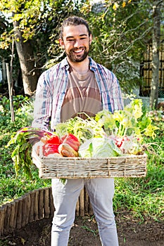 Portrait of confident gardener with vegetables in basket at garden