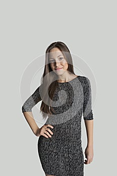 Portrait of confident girl in dress posing against gray background