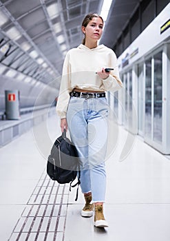 Portrait of a confident girl in the subway, holding a mobile phone photo