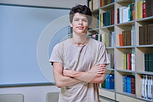 Portrait of confident guy college student looking at camera inside library