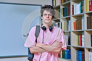 Portrait of confident guy college student looking at camera inside library