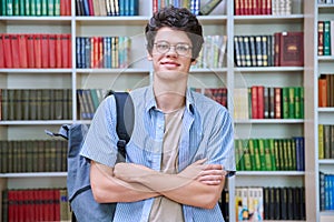 Portrait of confident guy college student looking at camera inside library