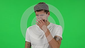 Portrait of confident guy is showing disgust for bad smell or taste. Green screen