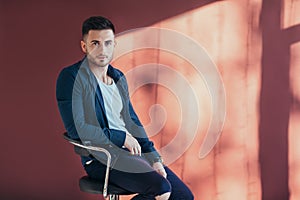 Portrait of confident and handsome man sitting on chair with cop