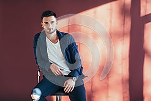 Portrait of confident and handsome man sitting on chair with cop