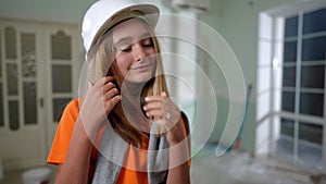 Portrait of confident happy teenage girl in white hard hat looking around smiling. Positive pretty cute Caucasian