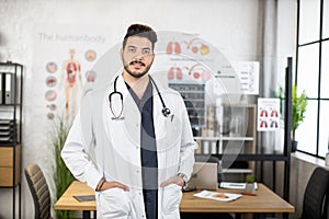 Portrait of confident indian doctor posing at cabinet