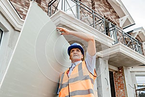 Portrait of confident indian male construction worker at construction site hold in hands cardboard Drywall.