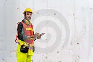 Portrait of confident inspector standing in front of containers in port